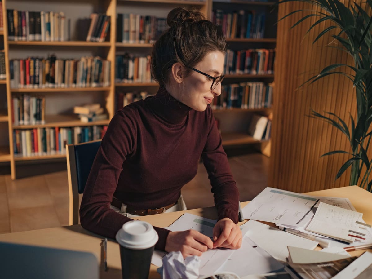 A candidate working through study notes at a library desk.